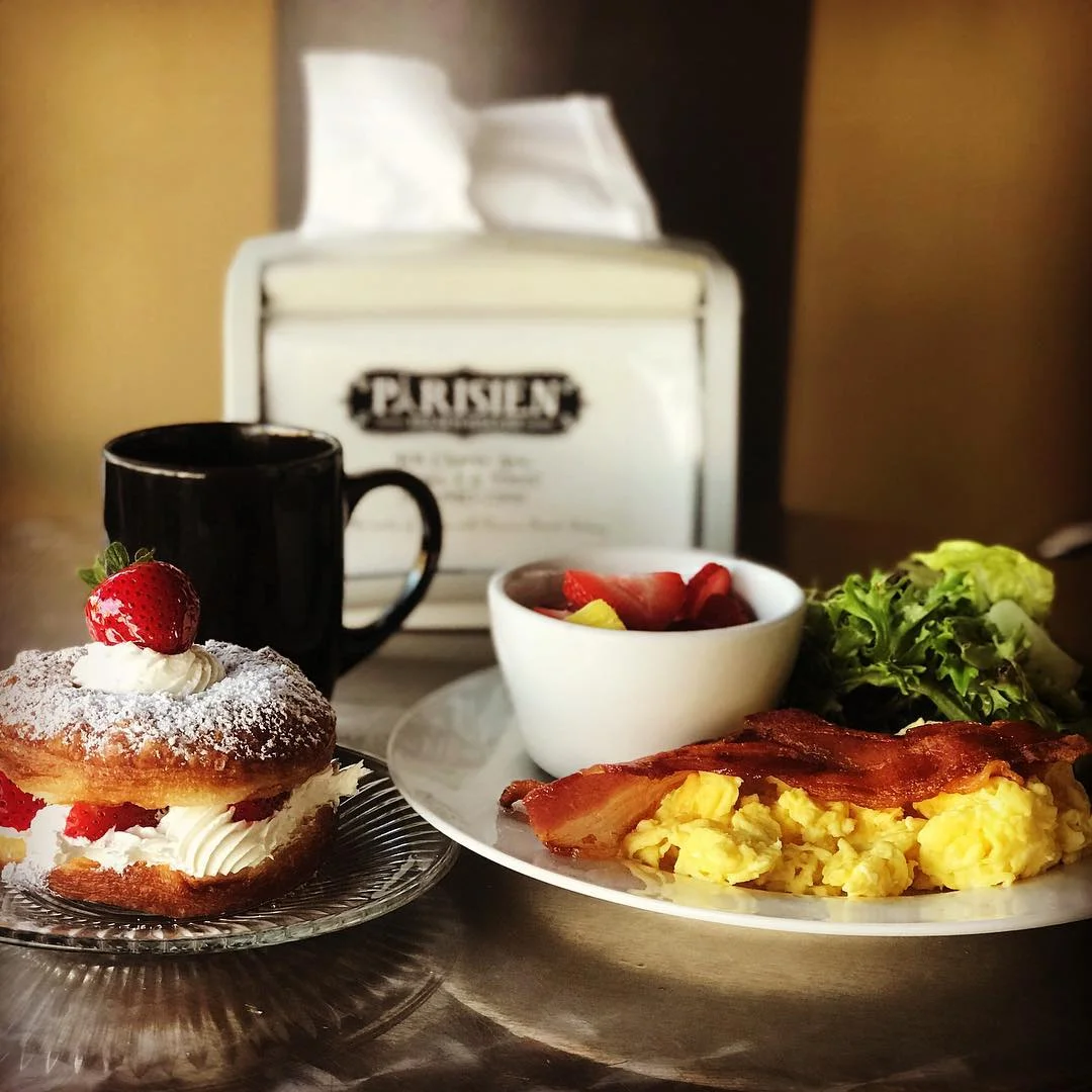 Parisien Bakery breakfast — pastry, scrambled eggs, bacon, fresh fruit and coffee